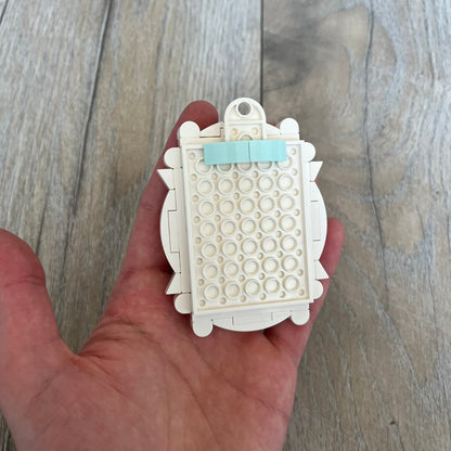 LEGO White Frame Make and Take Build is a limited promotional LEGO set distributed as an exclusive “make & take” event and not available for retail purchase. The model features a fully white 3D frame styled like a picture frame, designed for use as a photo holder. The back includes a hole for hanging or display.