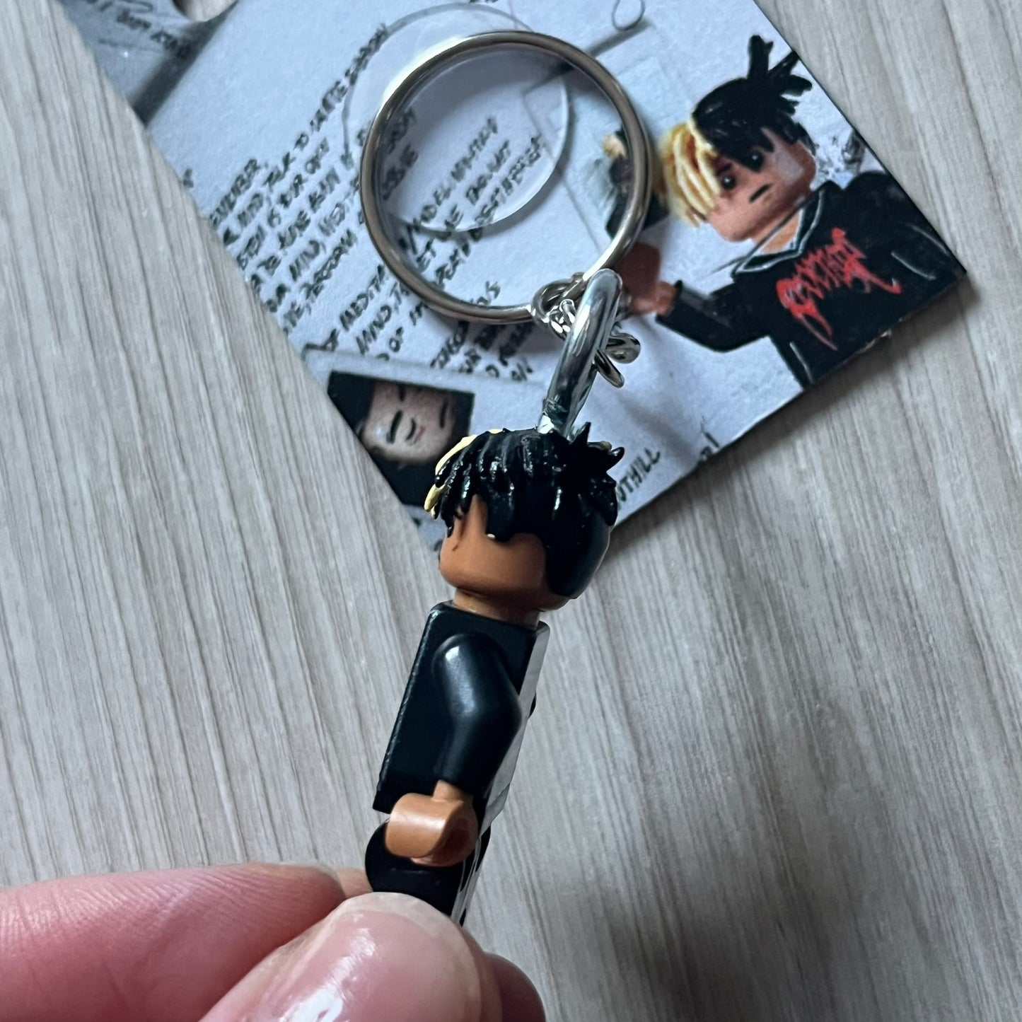 Lego XXXTentacion “XXXBlocktentacion” keychain featuring a custom Lego figure of XXXTentacion in a black/red revenge hoodie, with his classic split black and beige dreads in 3D. The figure is attached to a Lego-style recreation of the 2017 '17' album cover, reimagined in brick graphics. A great tribute and a creative collectible that merges music culture with fan-made Lego artistry, made by TheCanvasDon.