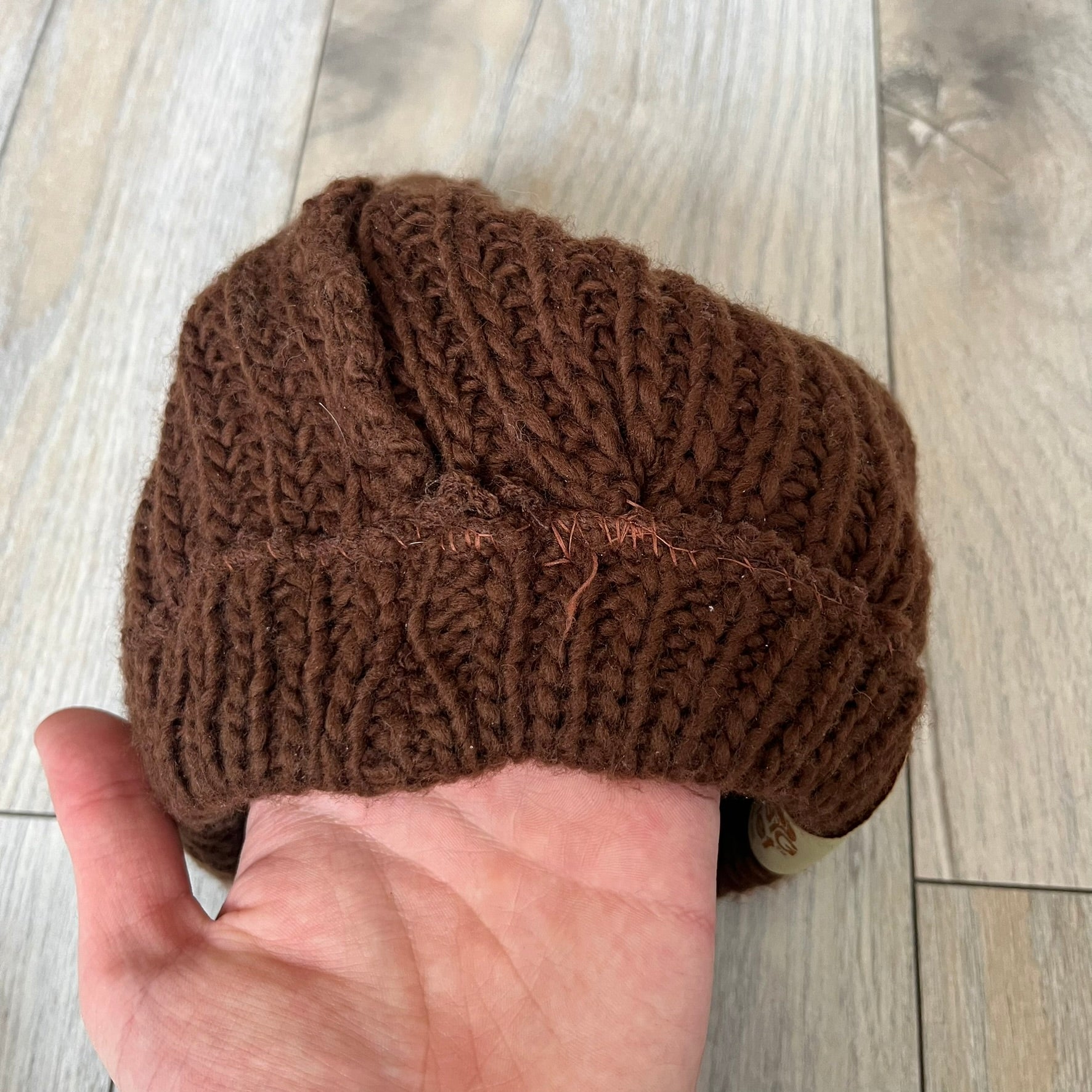 LittleBigPlanet 2009 Europe Exclusive Sackboy Beanie is an officially licensed brown knit beanie made from 100% acrylic. The design is styled after Sackboy and features a beige front tag with an orange Sackboy figure, LittleBigPlanet logo, and SCEE 2009 licensing. This item was released exclusively in the European region. Super rare and rarely seen for sale.