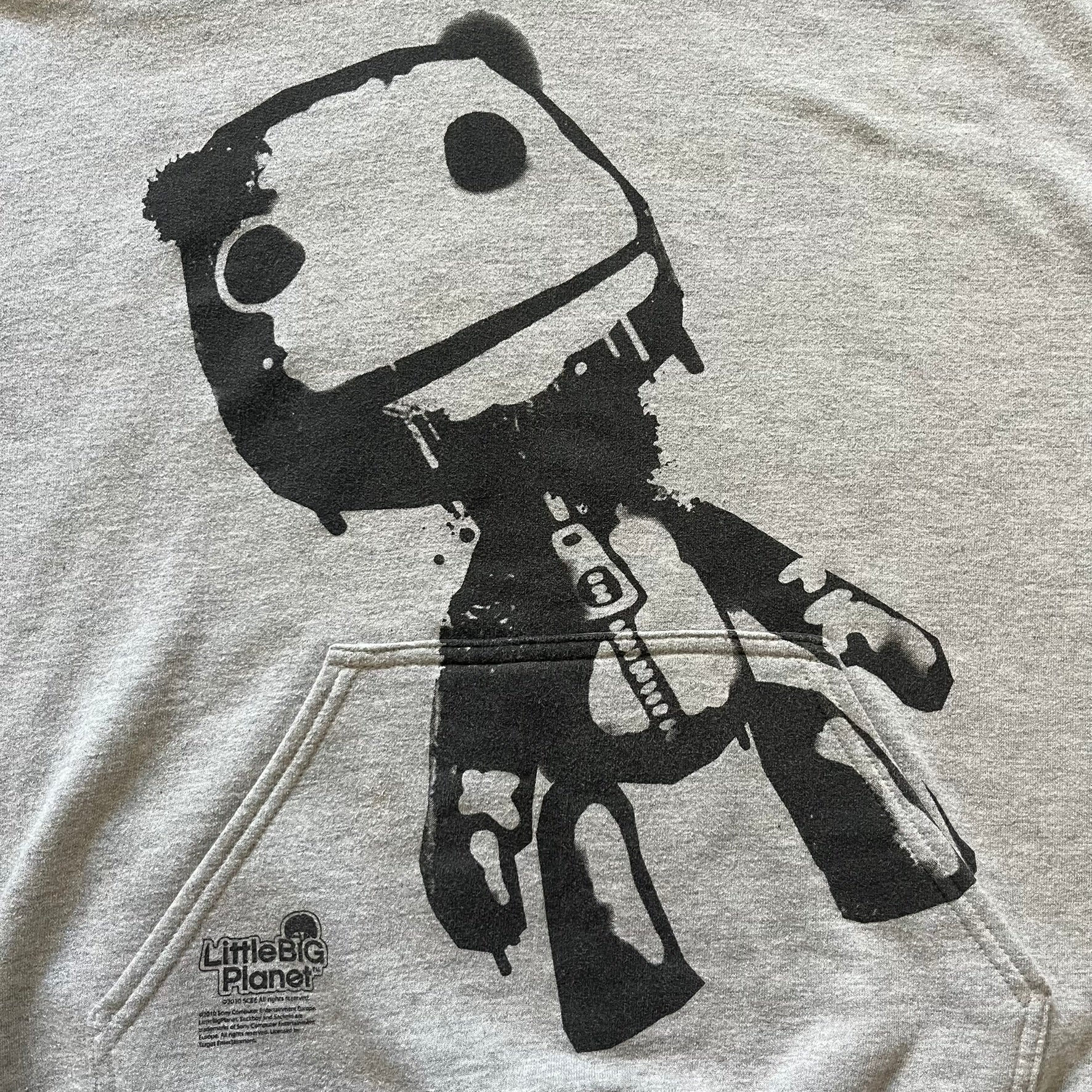 Ultra-rare Little Big Planet hoodie from 2010, made on a Gildan Heavy Blend. Showcases a graffiti like print with Sackboy and logo LBP branding on the pocket with Sony/SCEE licensing. This piece is nearly impossible to find today, making it a standout collectible for fans.