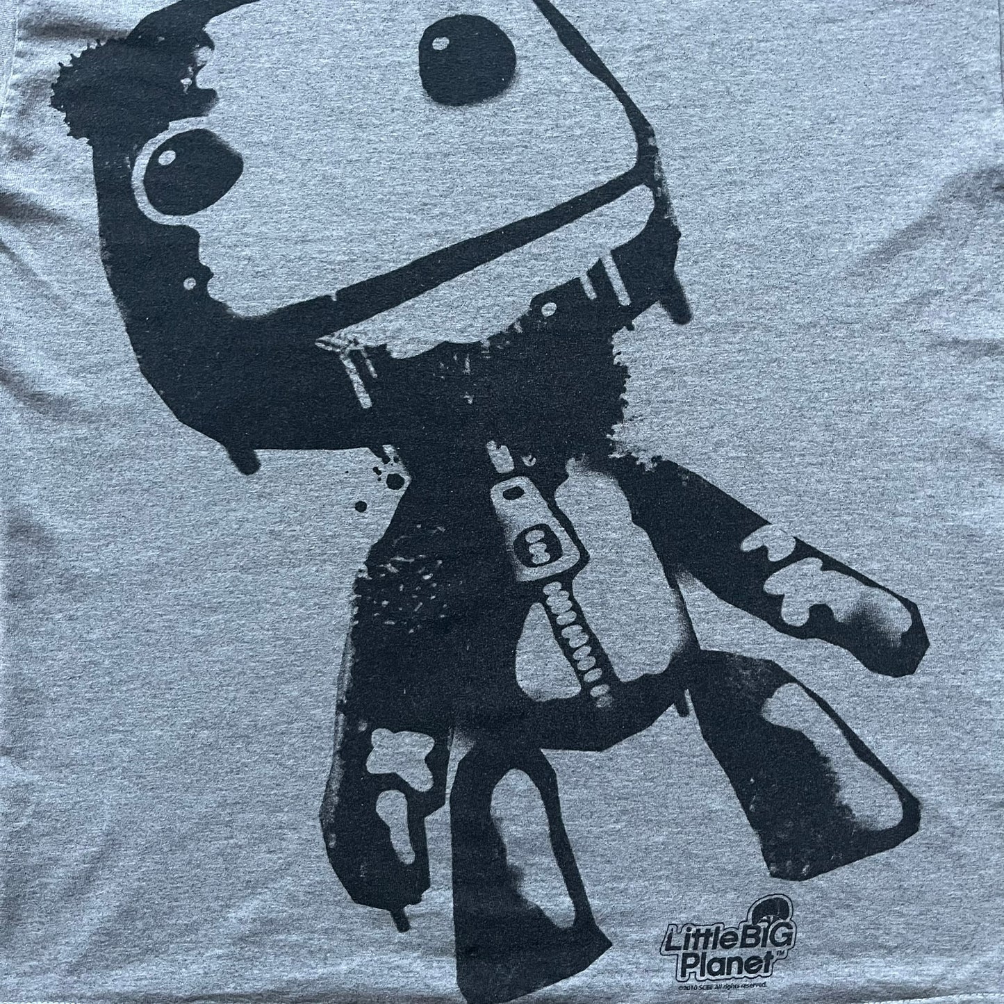 Very-rare Little Big Planet t-shirt from 2010, made on a Gildan Ultra Cotton. Showcases a graffiti like print with Sackboy and LBP logo branding in the bottom right corner with Sony/SCEE licensing. One of the rarest LBP pieces, this t-shirt is a true grail for fans and collectors.