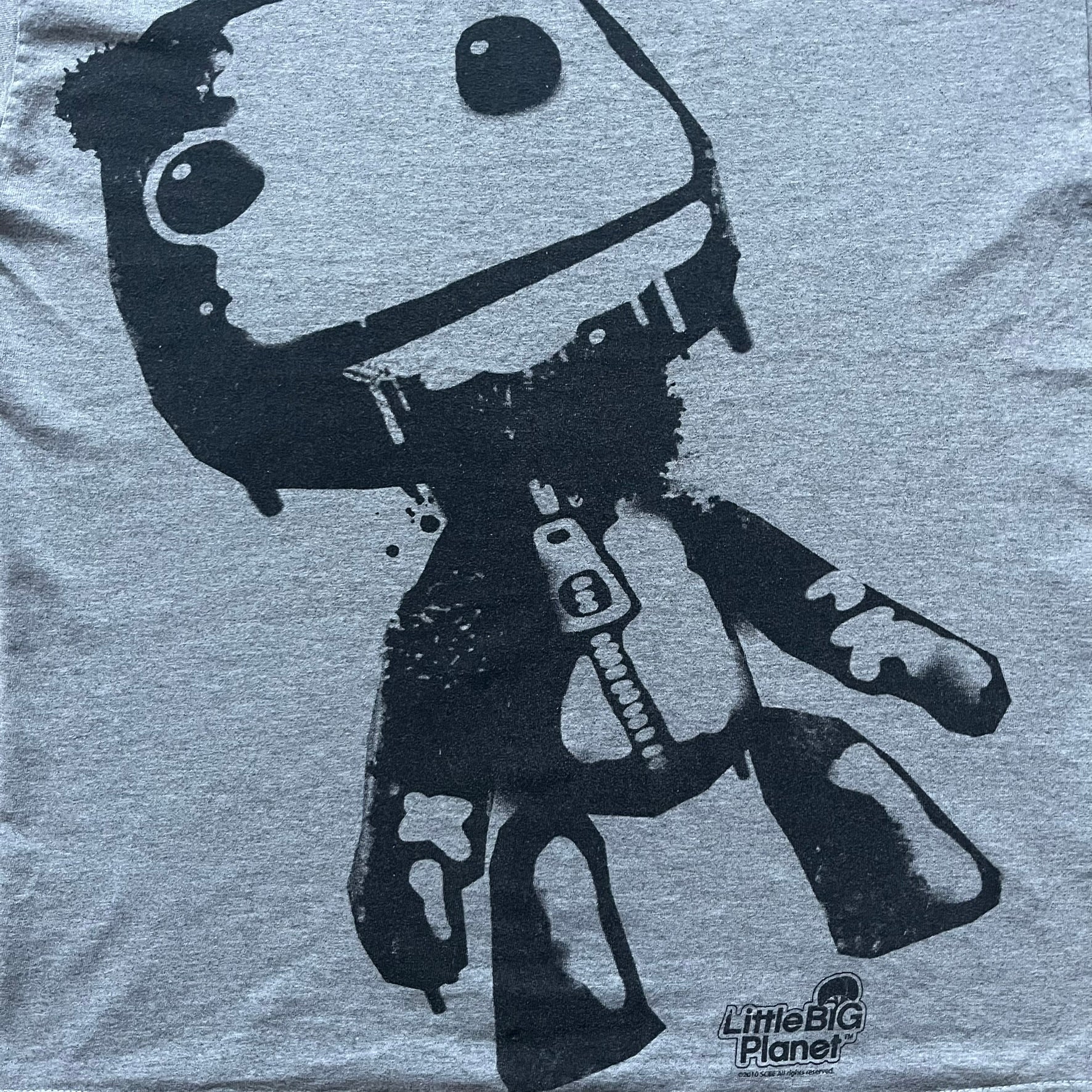 Very-rare Little Big Planet t-shirt from 2010, made on a Gildan Ultra Cotton. Showcases a graffiti like print with Sackboy and LBP logo branding in the bottom right corner with Sony/SCEE licensing. One of the rarest LBP pieces, this t-shirt is a true grail for fans and collectors.