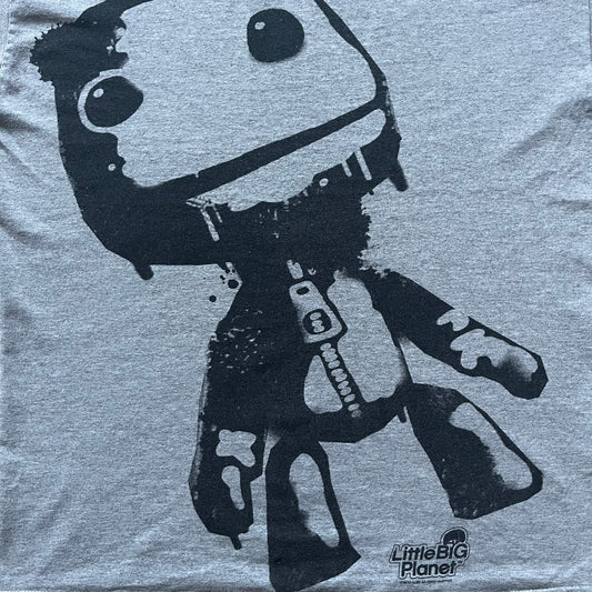 Very-rare Little Big Planet t-shirt from 2010, made on a Gildan Ultra Cotton. Showcases a graffiti like print with Sackboy and LBP logo branding in the bottom right corner with Sony/SCEE licensing. One of the rarest LBP pieces, this t-shirt is a true grail for fans and collectors.