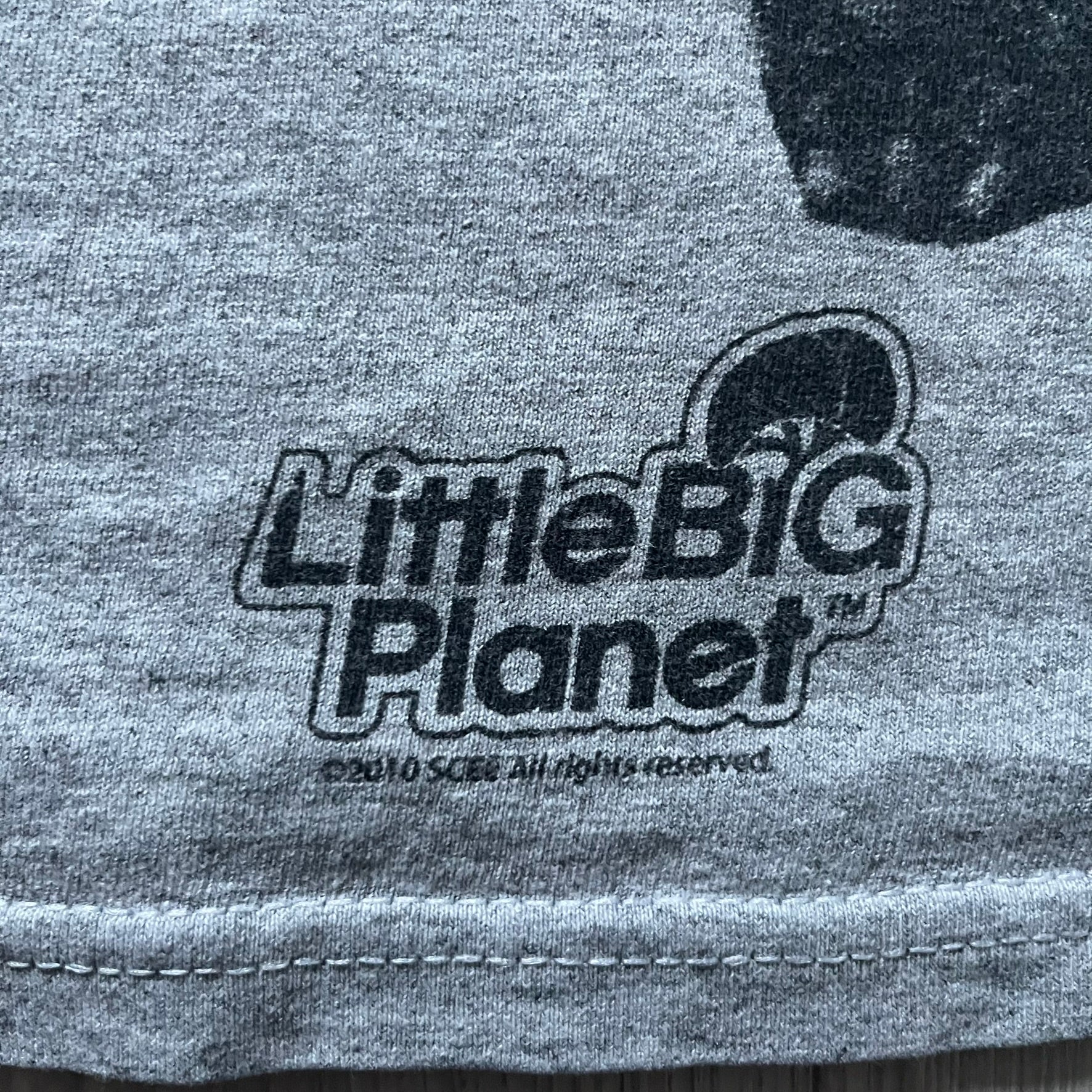 Very-rare Little Big Planet t-shirt from 2010, made on a Gildan Ultra Cotton. Showcases a graffiti like print with Sackboy and LBP logo branding in the bottom right corner with Sony/SCEE licensing. One of the rarest LBP pieces, this t-shirt is a true grail for fans and collectors.