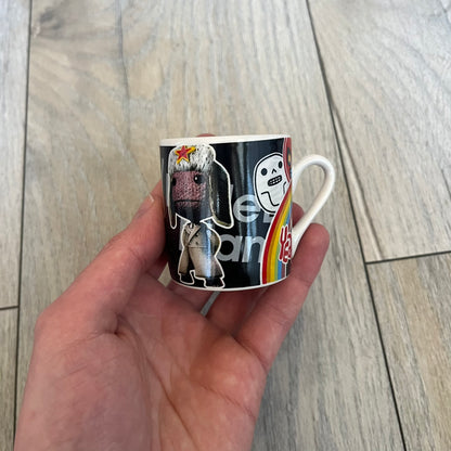 LittleBigPlanet 2011 Collectable Mini Mugs + Saucers Set is a 4-piece espresso set featuring characters from the LittleBigPlanet series, including Sackboy, Marvin the Disco Dancer, Gloria, and Yuri Army Sackboy. Each mini mug includes a wraparound character graphic with the LittleBigPlanet logo and comes with a matching saucer printed on the top. The set is officially licensed by Sony Computer Entertainment, includes a display box, and carries SCEE 2011 licensing on the base of the mugs and saucers.