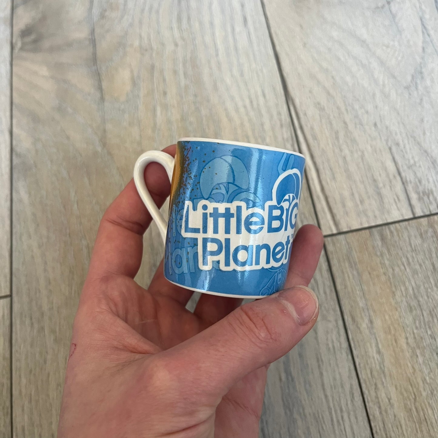 LittleBigPlanet 2011 Collectable Mini Mugs + Saucers Set is a 4-piece espresso set featuring characters from the LittleBigPlanet series, including Sackboy, Marvin the Disco Dancer, Gloria, and Yuri Army Sackboy. Each mini mug includes a wraparound character graphic with the LittleBigPlanet logo and comes with a matching saucer printed on the top. The set is officially licensed by Sony Computer Entertainment, includes a display box, and carries SCEE 2011 licensing on the base of the mugs and saucers.