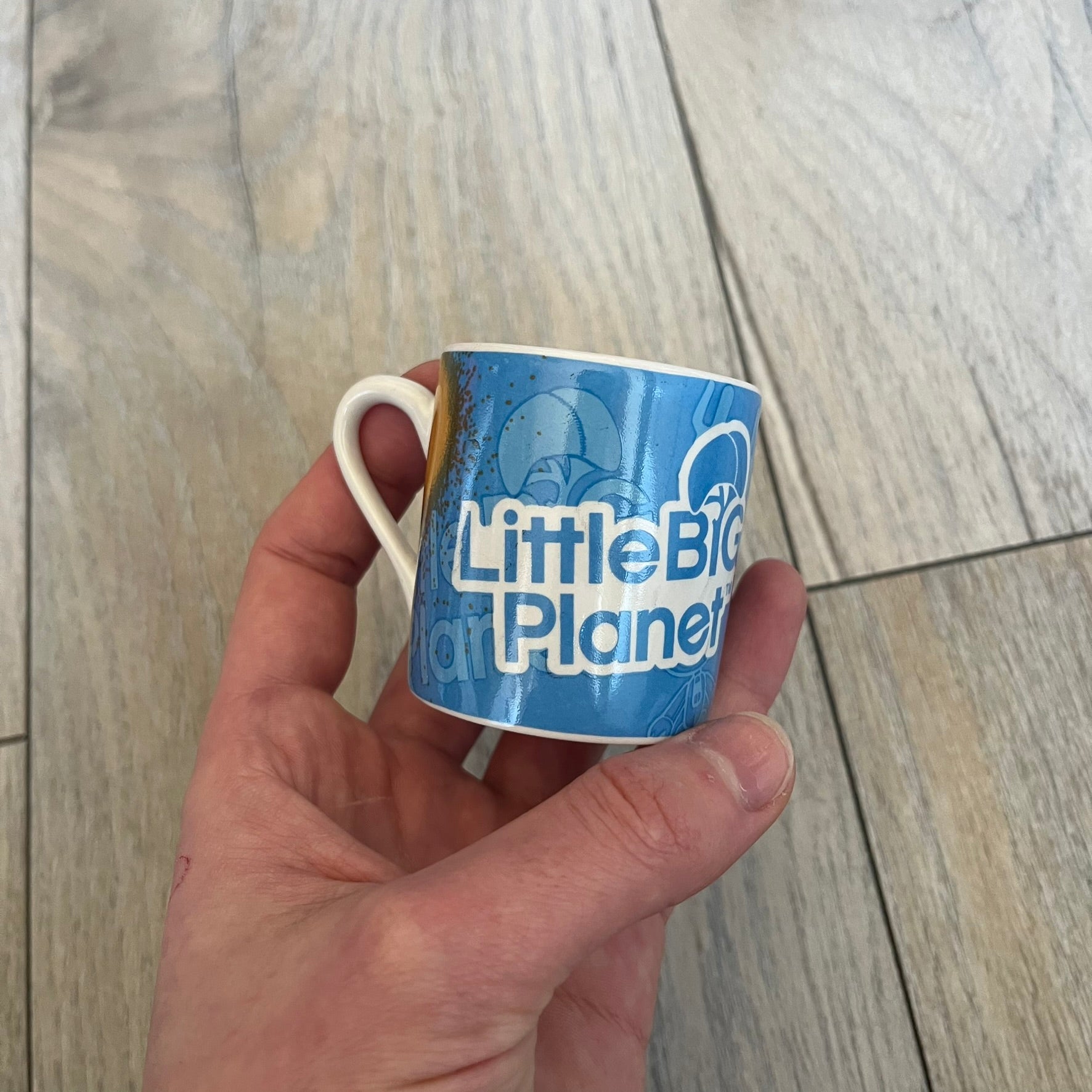 LittleBigPlanet 2011 Collectable Mini Mugs + Saucers Set is a 4-piece espresso set featuring characters from the LittleBigPlanet series, including Sackboy, Marvin the Disco Dancer, Gloria, and Yuri Army Sackboy. Each mini mug includes a wraparound character graphic with the LittleBigPlanet logo and comes with a matching saucer printed on the top. The set is officially licensed by Sony Computer Entertainment, includes a display box, and carries SCEE 2011 licensing on the base of the mugs and saucers.
