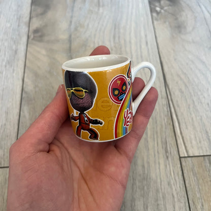 LittleBigPlanet 2011 Collectable Mini Mugs + Saucers Set is a 4-piece espresso set featuring characters from the LittleBigPlanet series, including Sackboy, Marvin the Disco Dancer, Gloria, and Yuri Army Sackboy. Each mini mug includes a wraparound character graphic with the LittleBigPlanet logo and comes with a matching saucer printed on the top. The set is officially licensed by Sony Computer Entertainment, includes a display box, and carries SCEE 2011 licensing on the base of the mugs and saucers.