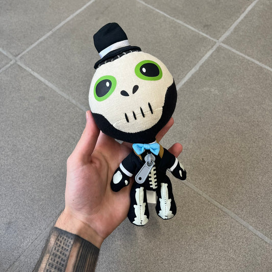 Little Big Planet 2 Voodoo Sackboy 2010 Plush is an officially Sony-licensed Sackboy plush dressed as a voodoo witch doctor, featuring a skull face, green eyes, a tiny top hat, and a blue bow tie, finished with the signature gray plastic front zipper. Fully jointed, moveable, and poseable, it carries a licensed 2010 Senario tag.