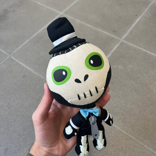 Little Big Planet 2 Voodoo Sackboy 2010 Plush is an officially Sony-licensed Sackboy plush dressed as a voodoo witch doctor, featuring a skull face, green eyes, a tiny top hat, and a blue bow tie, finished with the signature gray plastic front zipper. Fully jointed, moveable, and poseable, it carries a licensed 2010 Senario tag.
