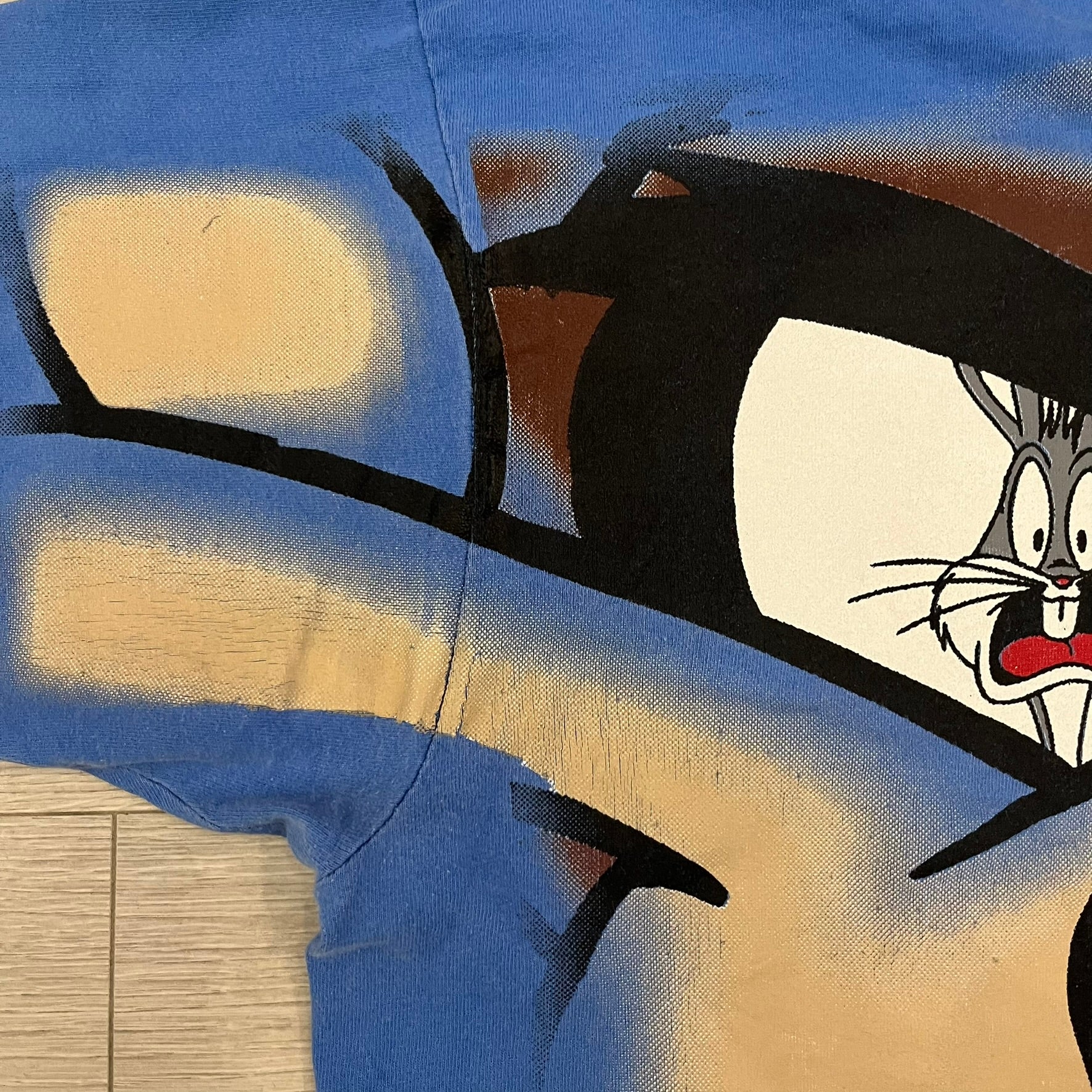 Looney Tunes “Taz & Bugs Bunny” 1997 Freeze Tee featuring a blue base with an all-over front print. The graphic shows Taz with an angry expression and Bugs Bunny reflected in his eyes, with 1997 Warner Bros. Freeze licensing printed below. Made in the USA from 100% cotton.