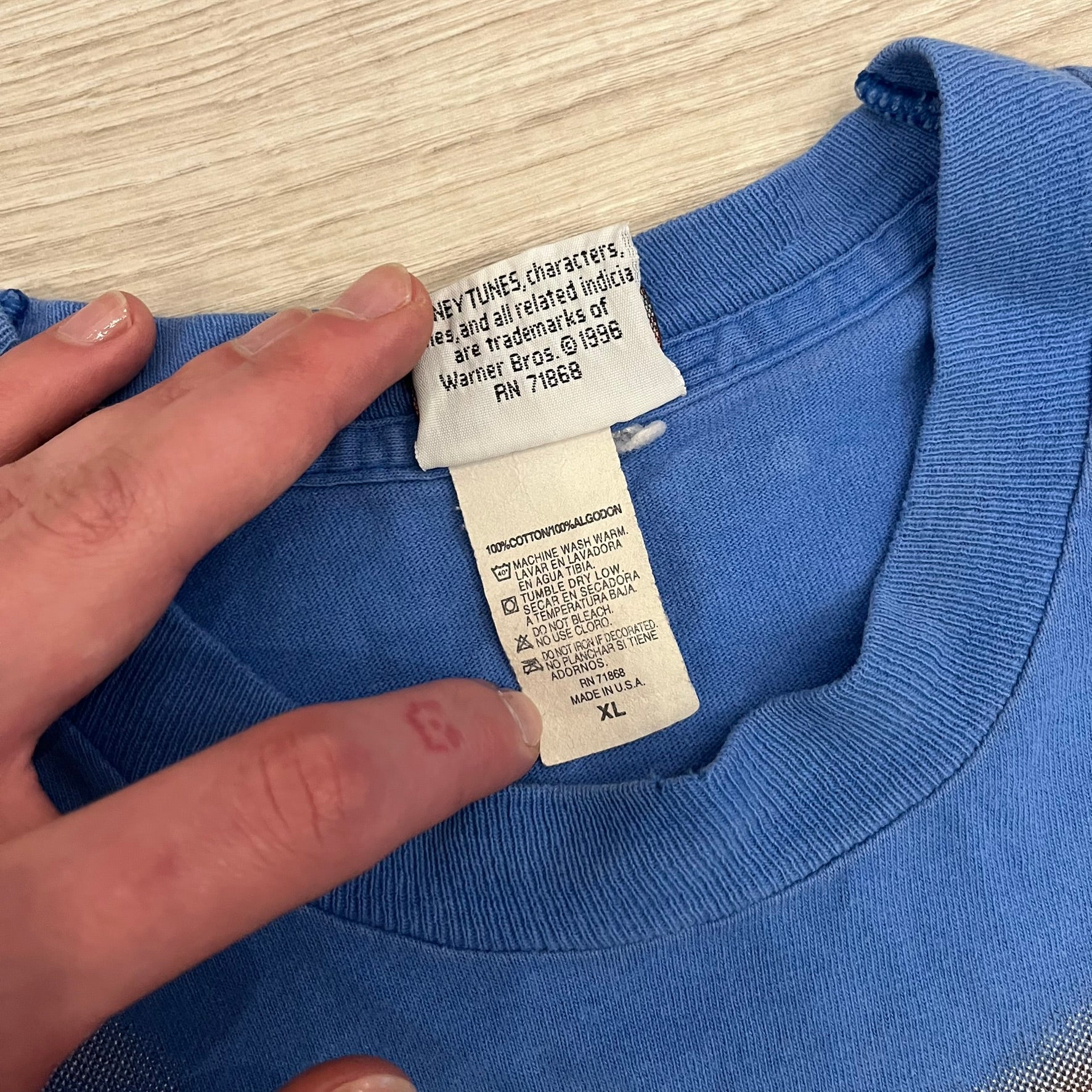 Looney Tunes “Taz & Bugs Bunny” 1997 Freeze Tee featuring a blue base with an all-over front print. The graphic shows Taz with an angry expression and Bugs Bunny reflected in his eyes, with 1997 Warner Bros. Freeze licensing printed below. Made in the USA from 100% cotton.