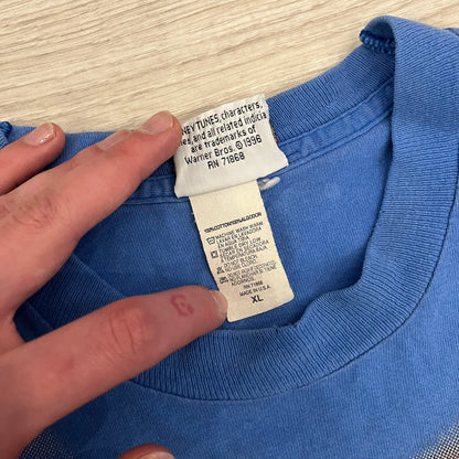 Looney Tunes “Taz & Bugs Bunny” 1997 Freeze Tee featuring a blue base with an all-over front print. The graphic shows Taz with an angry expression and Bugs Bunny reflected in his eyes, with 1997 Warner Bros. Freeze licensing printed below. Made in the USA from 100% cotton.