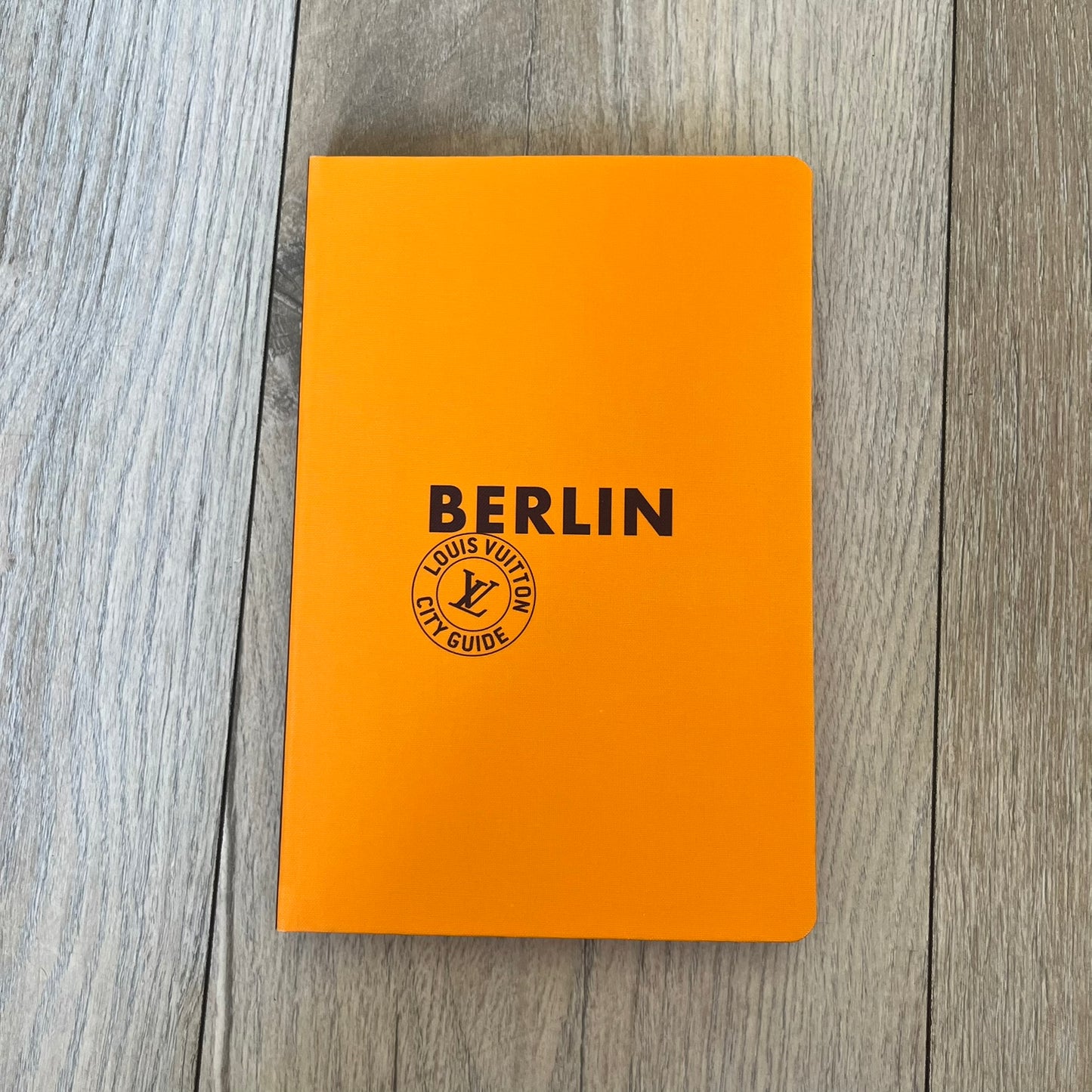 Louis Vuitton Berlin City Guide is an English-language travel guide with a cloth-bound hardcover. It includes recommendations for hotels, restaurants, museums, shopping, and cultural attractions throughout Berlin. The edition features guest contributions by Bénédicte Savoy, writing by Romain Charbon and Tristan Sechrest, and exclusive photography by Thierry Ardouin.