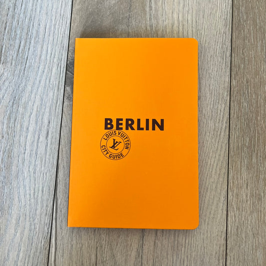 Louis Vuitton Berlin City Guide is an English-language travel guide with a cloth-bound hardcover. It includes recommendations for hotels, restaurants, museums, shopping, and cultural attractions throughout Berlin. The edition features guest contributions by Bénédicte Savoy, writing by Romain Charbon and Tristan Sechrest, and exclusive photography by Thierry Ardouin.