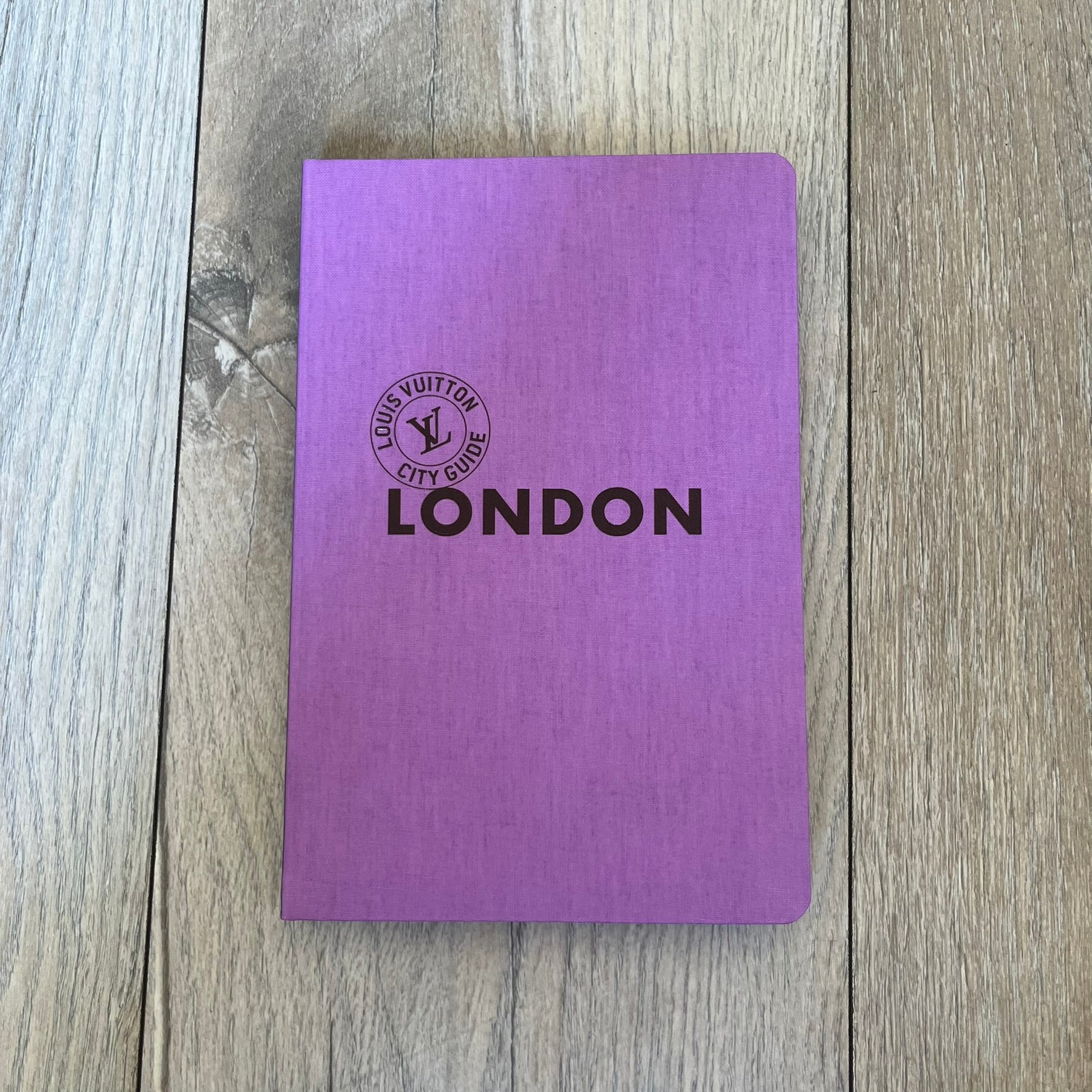 Louis Vuitton London City Guide is an English-language travel guide with a cloth-bound hardcover. It includes recommendations for hotels, restaurants, museums, shopping, and cultural locations across London. The edition features guest contributions by Richard Deverell, writing by Richard Cook, and exclusive photography by Grégoire Eloy.
