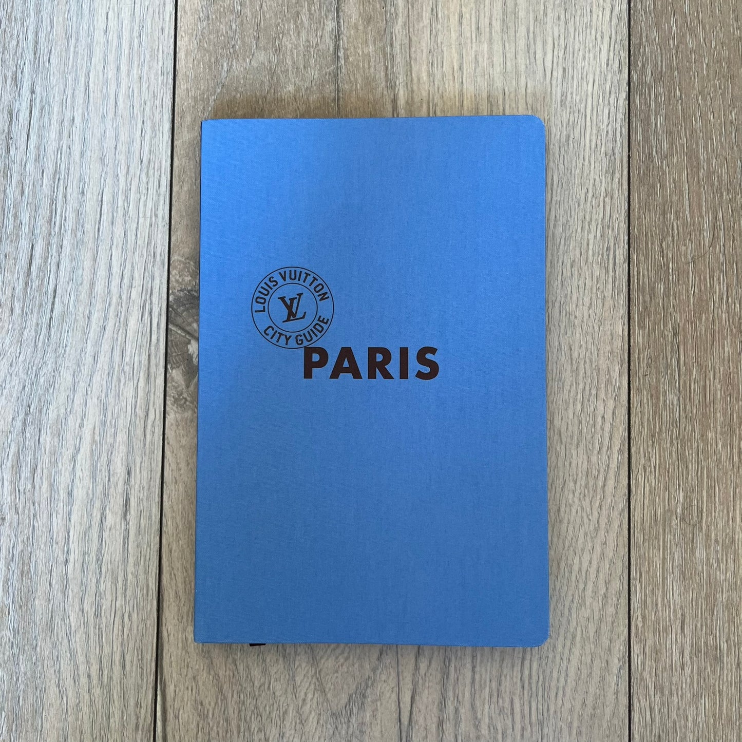  Louis Vuitton Paris City Guide is an English-language travel guide featuring 360 pages with a cloth-bound hardcover. Measuring 12.4 × 9.5 inches, it includes recommendations for hotels, restaurants, museums, shopping, and cultural attractions throughout Paris. The edition features guest contributions by Enzo Lefort, photography by the Tendance Floue collective, and writing by Pierre Leonforte, Pierre Groppo, Katia Kulawick-Assante, François Simon, Isabelle Valembras-Dahirel, Marie-Hélène Brunet-Lhoste, Lau