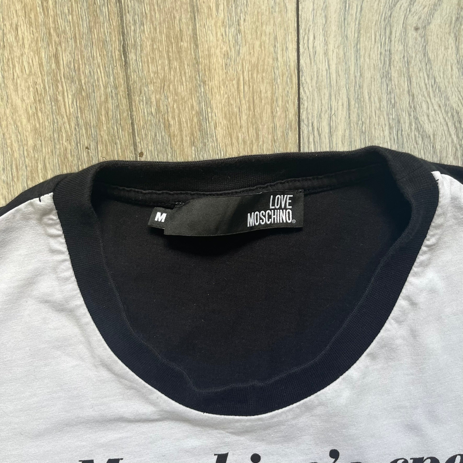 Love Moschino 2010s Carrot Tee is a black and white T-shirt with black sleeves and back panel. The front features Love Moschino branding above two illustrated carrots, with large red “CARROT” text underneath and “Price 20 Cents” text below. The front graphic is designed in the style of a vintage carrot advertisement.

