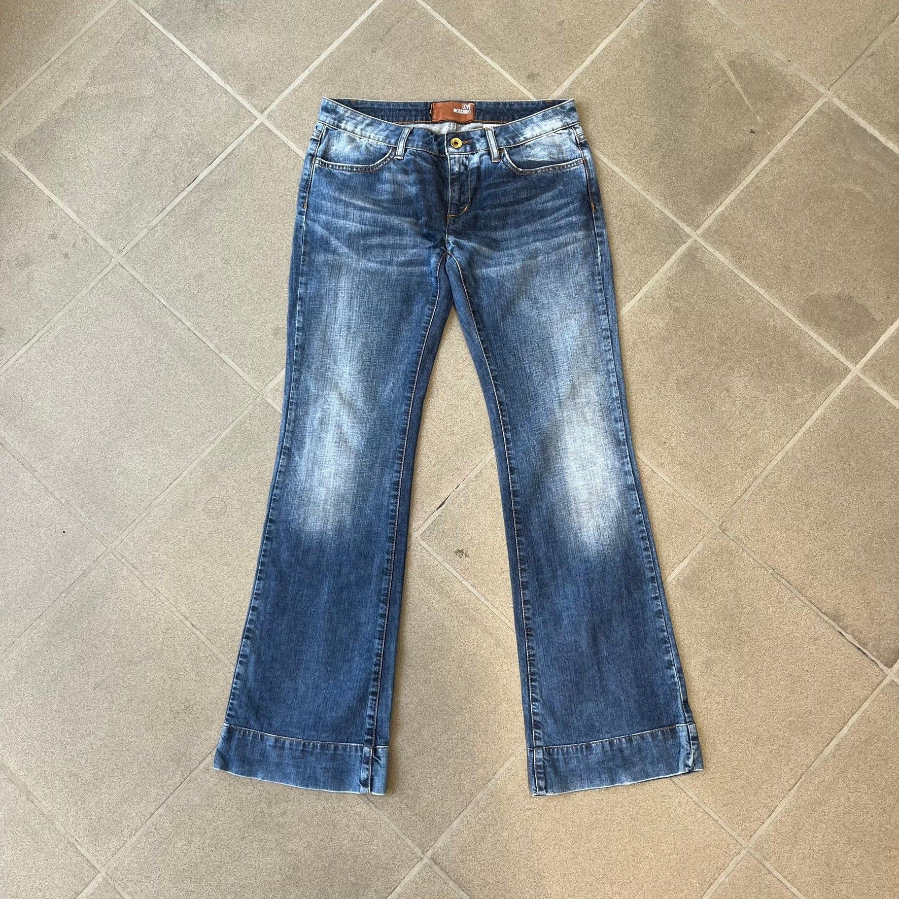 Love Moschino Hearts Bootcut Jeans feature blue denim with a white washed effect around the knees and a bootcut construction. They have a gold-tone Love Moschino button and two back pockets with raised horizontal heart-shaped stitching. Made from 98% cotton and 2% elastane.
