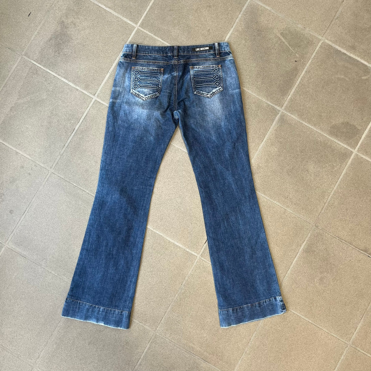 Love Moschino Hearts Bootcut Jeans feature blue denim with a white washed effect around the knees and a bootcut construction. They have a gold-tone Love Moschino button and two back pockets with raised horizontal heart-shaped stitching. Made from 98% cotton and 2% elastane.
