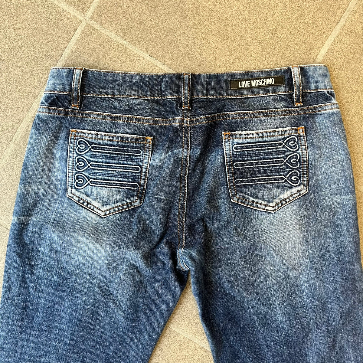 Love Moschino Hearts Bootcut Jeans feature blue denim with a white washed effect around the knees and a bootcut construction. They have a gold-tone Love Moschino button and two back pockets with raised horizontal heart-shaped stitching. Made from 98% cotton and 2% elastane.
