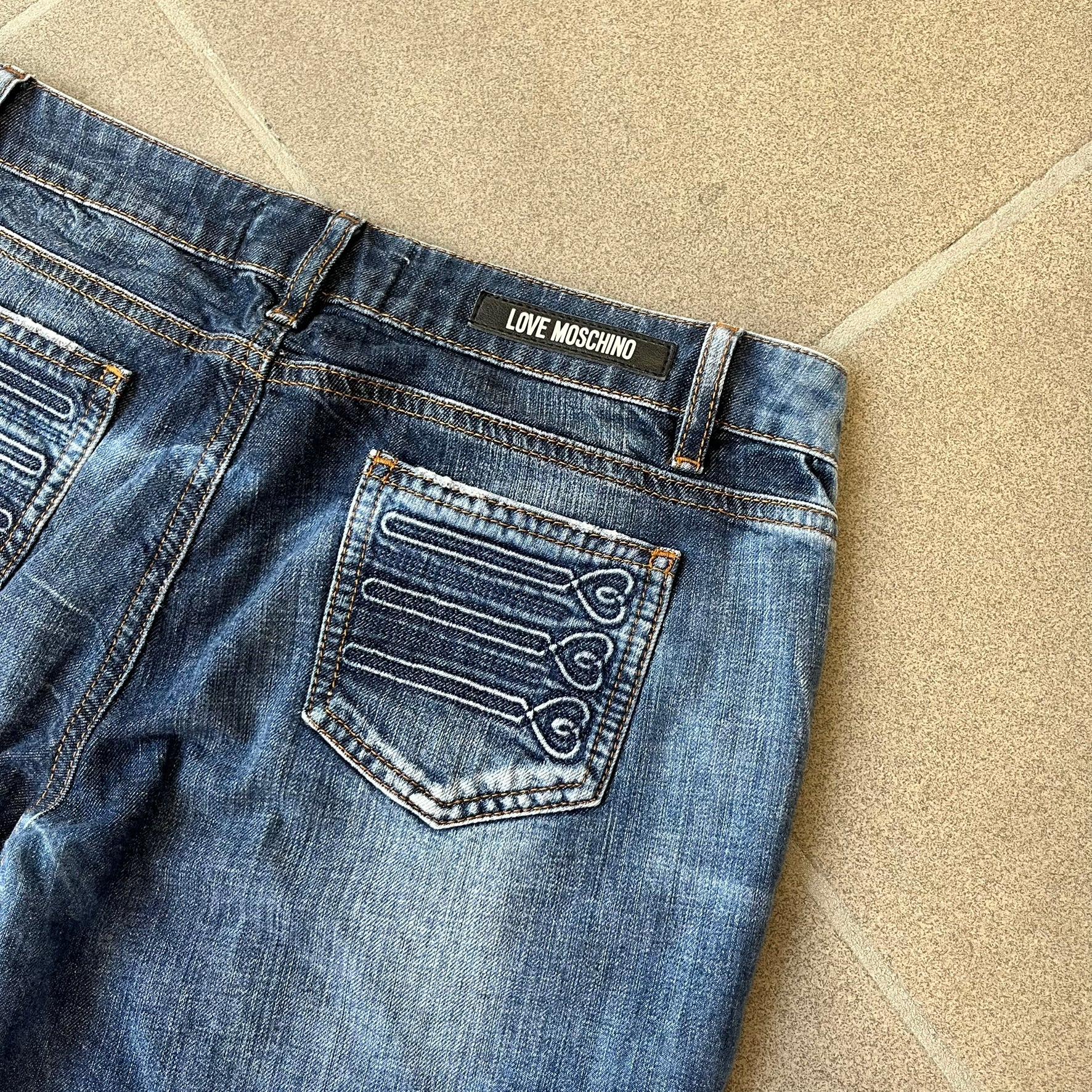 Love Moschino Hearts Bootcut Jeans feature blue denim with a white washed effect around the knees and a bootcut construction. They have a gold-tone Love Moschino button and two back pockets with raised horizontal heart-shaped stitching. Made from 98% cotton and 2% elastane.
