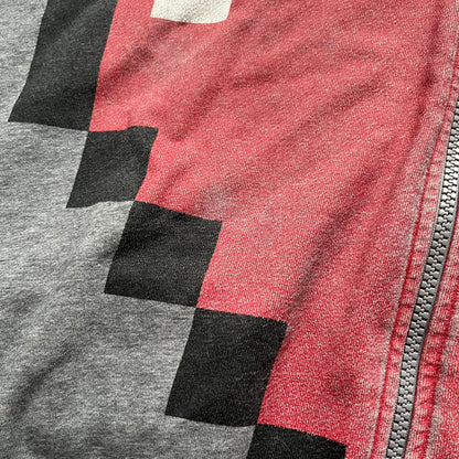 Love Moschino Pixel Heart Gray Hoodie is a gray zip-up hoodie featuring a large red pixel heart graphic on the front. It has slightly shorter-than-standard sleeves, long drawstrings, and a front zipper closure. The lower part includes Love Moschino logo detailing, completing the branded design.
