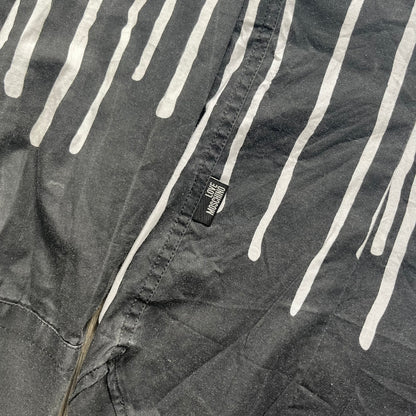 Love Moschino SS19 Dripping Paint Print Button-Up Shirt is a black and white shirt from the Spring/Summer 2019 collection. The upper portion is white, while the lower portion is black. The transition between the two sections features a dripping paint graphic extending downward from both sides into the black area. The button closure uses matching buttons, with white buttons on the white section and black buttons on the black section.
