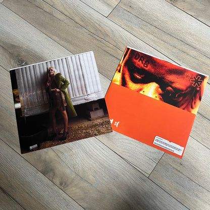 Lucki Drgs R Bad* 2026 Signed BRAZY 4 LUCKI Vinyl is a 2xLP release of Lucki’s fourth studio album, originally released on May 15, 2026. The set includes alternative front and back artwork, a widespine jacket, and printed inner sleeves with different graphics for each record. The vinyl records are transparent orange with black smoke effects throughout. The outer jacket features artwork of a girl shaving her head with the DRB logo cut into her hair. This copy is signed by Lucki in the upper left corner with 