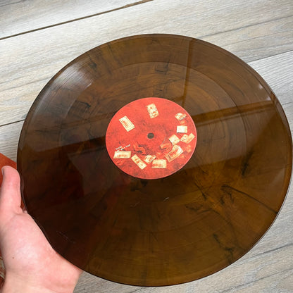 Lucki Drgs R Bad* 2026 Signed BRAZY 4 LUCKI Vinyl is a 2xLP release of Lucki’s fourth studio album, originally released on May 15, 2026. The set includes alternative front and back artwork, a widespine jacket, and printed inner sleeves with different graphics for each record. The vinyl records are transparent orange with black smoke effects throughout. The outer jacket features artwork of a girl shaving her head with the DRB logo cut into her hair. This copy is signed by Lucki in the upper left corner with 