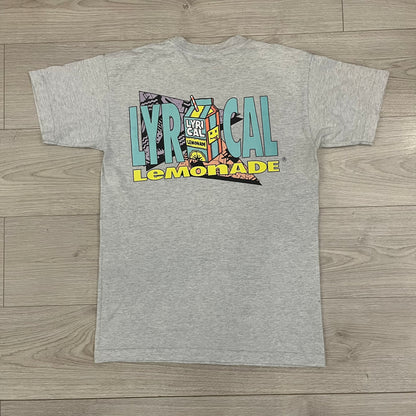 Lyrical Lemonade Everyday Essentials Gray T-Shirt in a gray colorway. Features a small Lyrical Lemonade carton graphic with an xP face printed on the left chest. The back displays a large Lyrical Lemonade logo with text and carton graphics in blue, yellow, and pink, from the Everyday Essentials line.