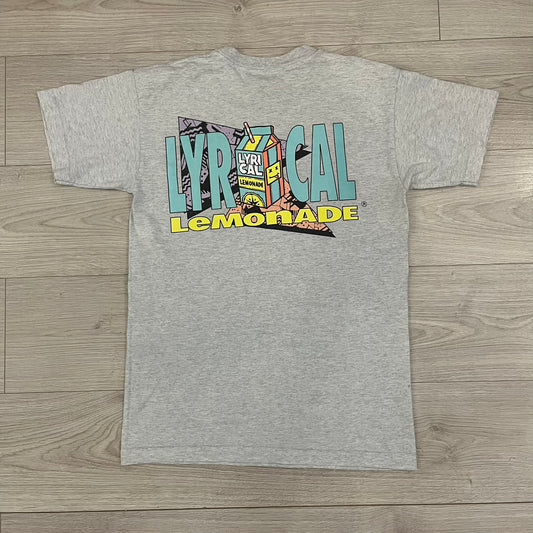 Lyrical Lemonade Everyday Essentials Gray T-Shirt in a gray colorway. Features a small Lyrical Lemonade carton graphic with an xP face printed on the left chest. The back displays a large Lyrical Lemonade logo with text and carton graphics in blue, yellow, and pink, from the Everyday Essentials line.