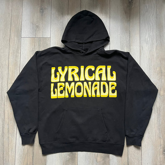 Lyrical Lemonade Everyday Essentials Yellow Logo Hoodie is a black pullover hoodie featuring a large two-tone yellow Lyrical Lemonade logo printed on the front. It includes an Everyday Essentials neck tag and classic comfortable hoodie construction.