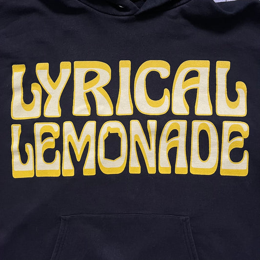 Lyrical Lemonade Everyday Essentials Yellow Logo Hoodie is a black pullover hoodie featuring a large two-tone yellow Lyrical Lemonade logo printed on the front. It includes an Everyday Essentials neck tag and classic comfortable hoodie construction.