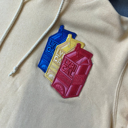 Lyrical Lemonade Triple Patch Yellow Hoodie features a yellow colorway with a layered triple lemonade box patch design on the left chest in red, yellow, and blue. Made from an 80/20 cotton-polyester blend, the hoodie includes a yellow Lyrical Lemonade neck tag.