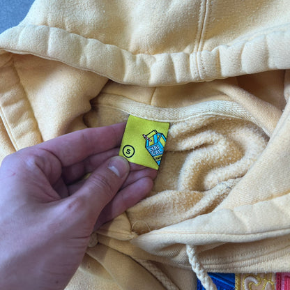 Lyrical Lemonade Triple Patch Yellow Hoodie features a yellow colorway with a layered triple lemonade box patch design on the left chest in red, yellow, and blue. Made from an 80/20 cotton-polyester blend, the hoodie includes a yellow Lyrical Lemonade neck tag.