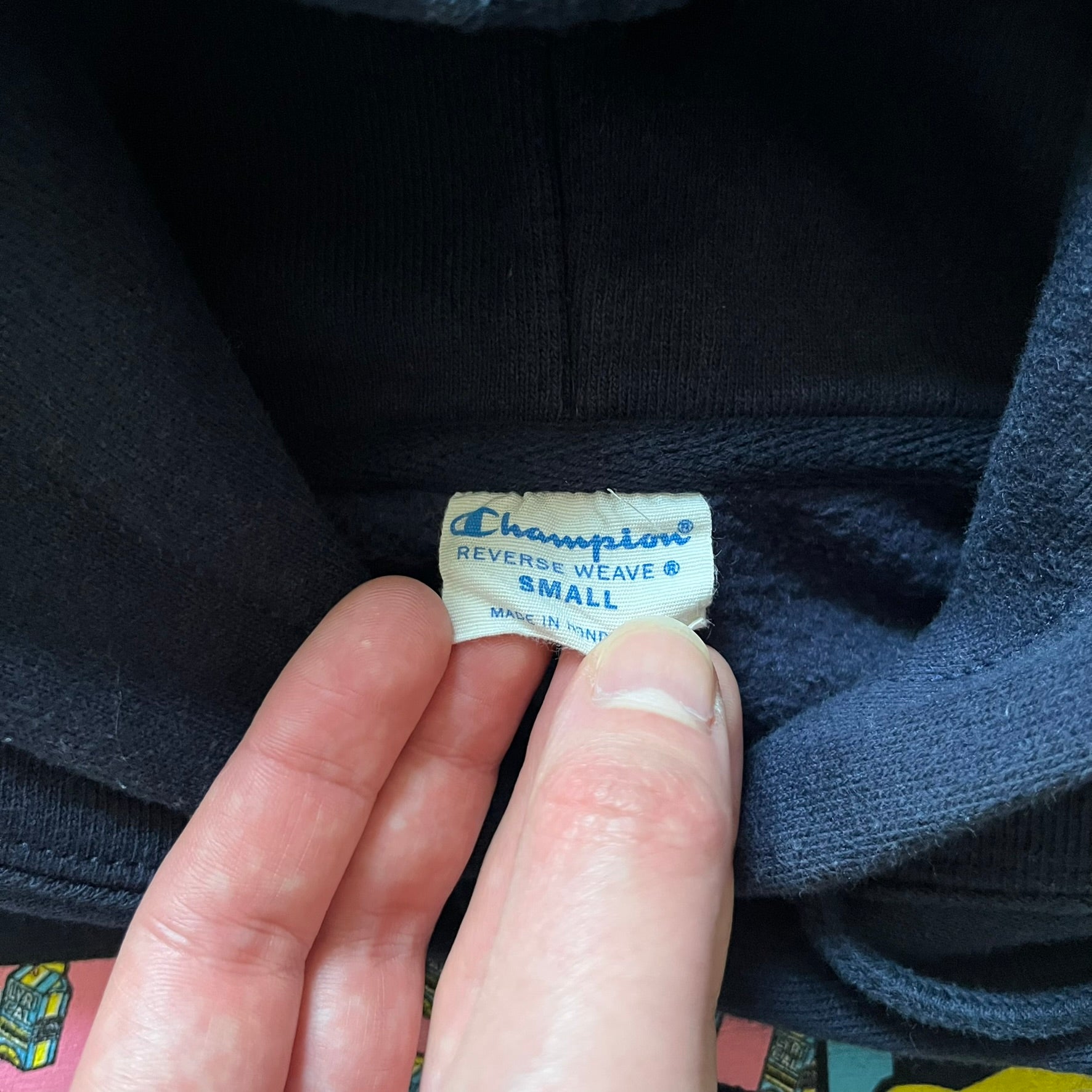 Lyrical Lemonade x MTV hoodie made on a Champion Reverse Weave blank. The front features a large pink Lyrical Lemonade “LL” logo based on MTV, filled with lemonade carton graphics, and white “Lyrical Lemonade” text printed underneath. Constructed with Champion’s heavyweight Reverse Weave fabric, finished with ribbed side panels and a small embroidered Champion logo on the sleeve near the hem.