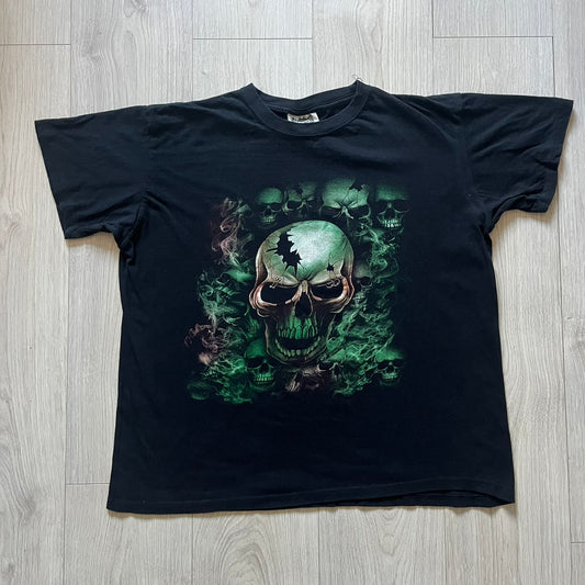 MC5 Boyc Skulls Tee in a wide, boxy-ish fit, crafted from high-quality cotton. The black tee features a large cracked skull with piercings on the front, surrounded by smaller skulls in white and green tones. A bold vintage-inspired graphic piece with strong visual impact.