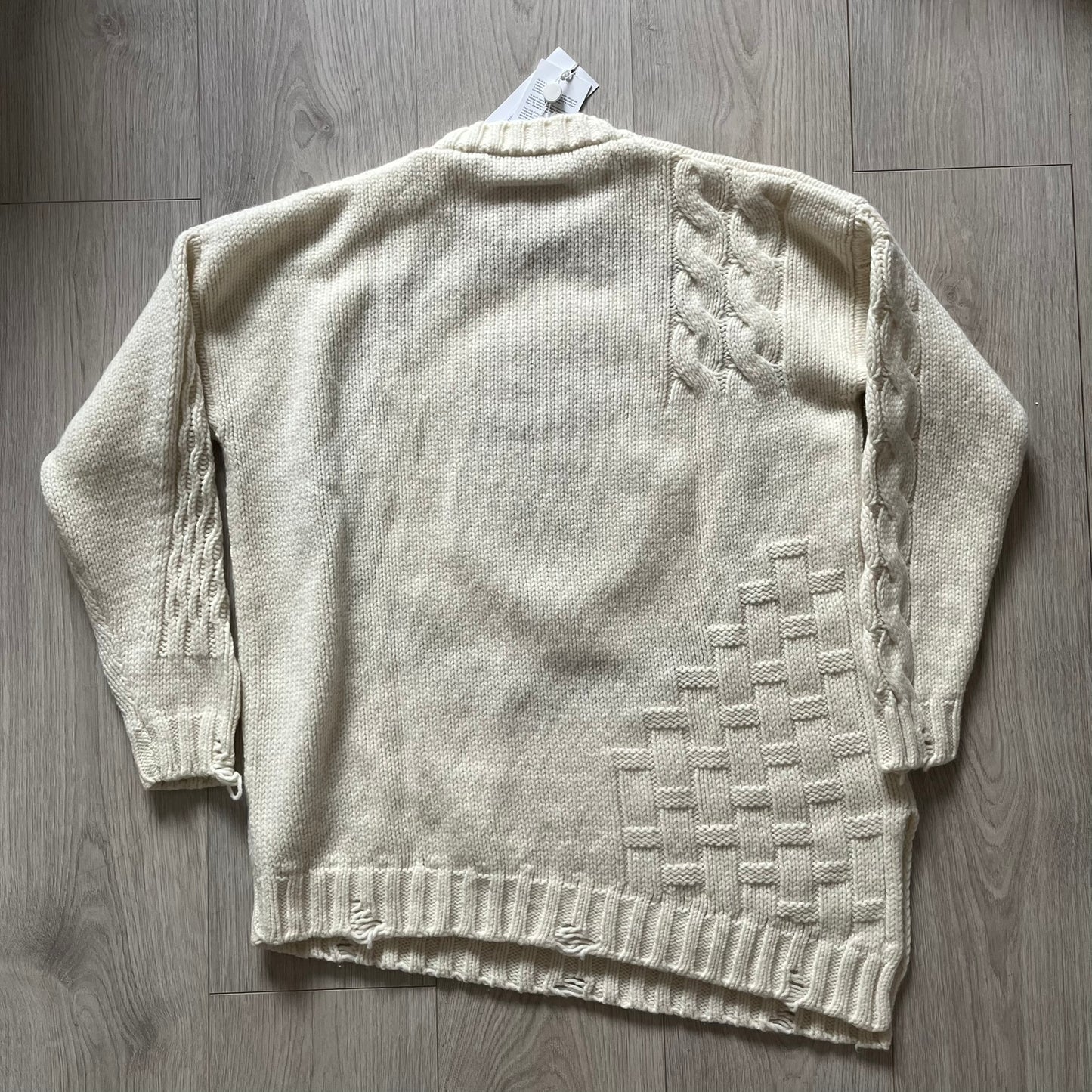 Beige knitted cardigan with geometric pattern on a wooden surface