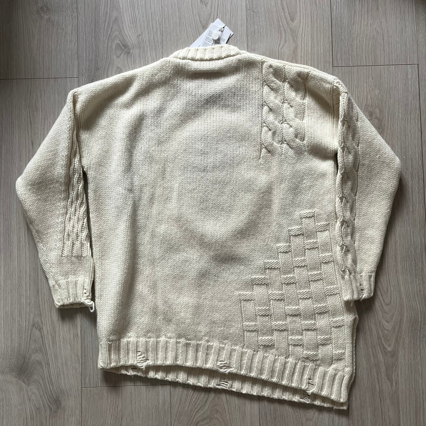 Beige knitted cardigan with geometric pattern on a wooden surface