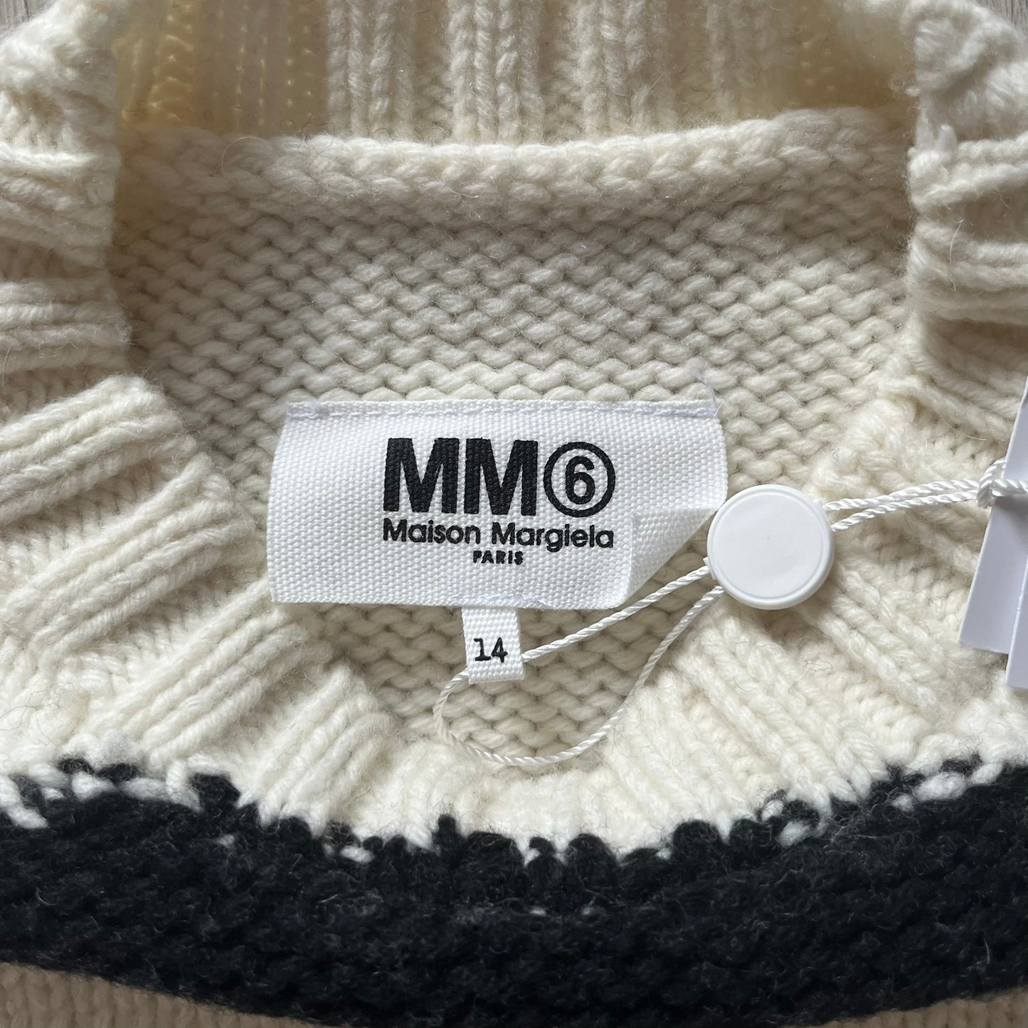 Close-up of a Maison Margiela label on a knitted garment with a tag.