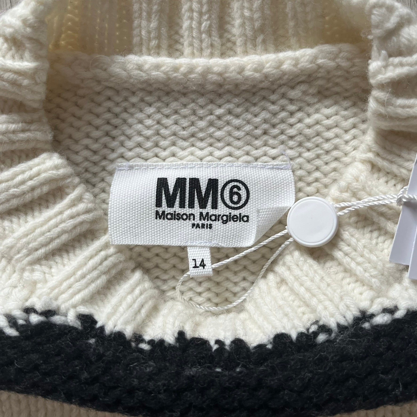 Close-up of a Maison Margiela label on a knitted garment with a tag.