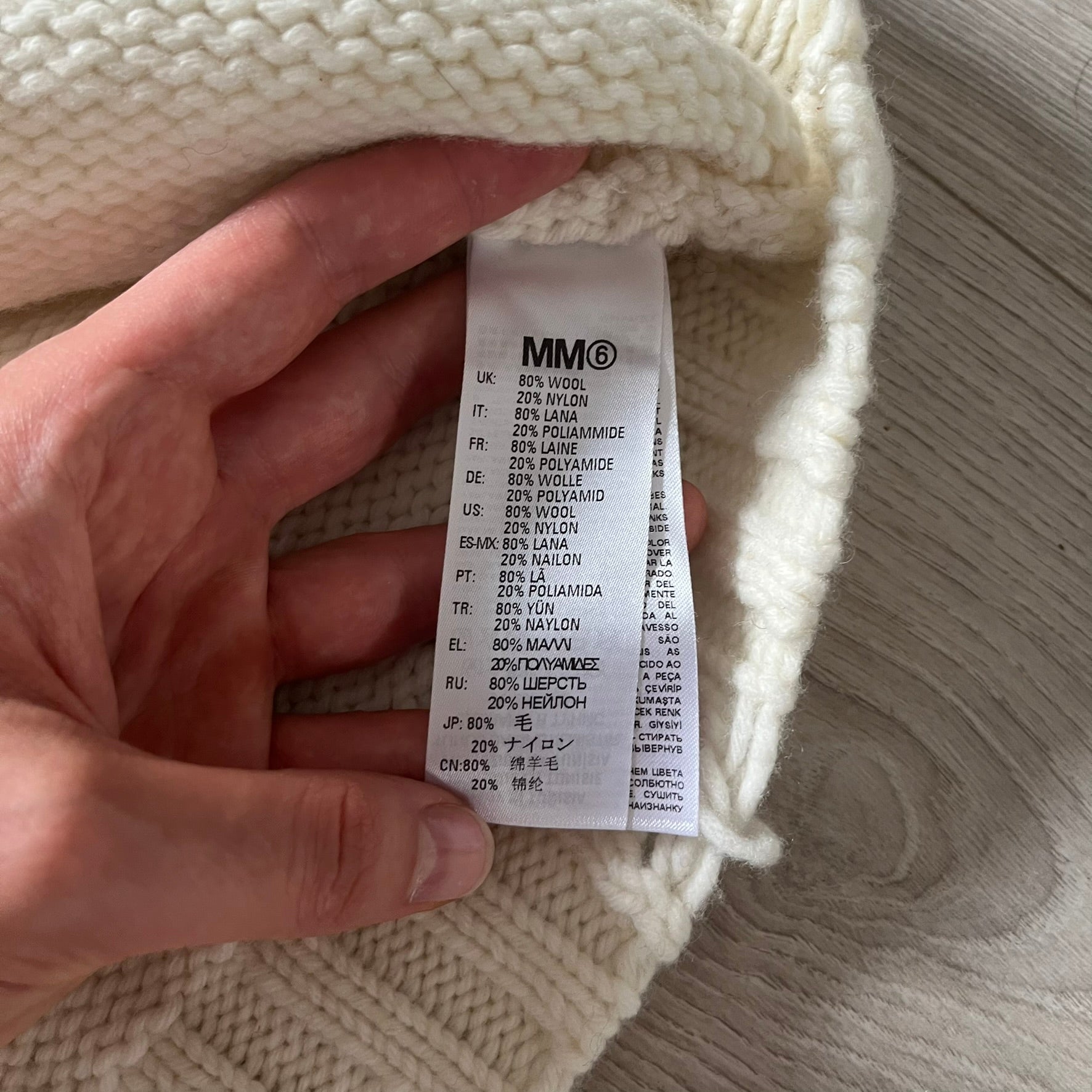 Hand holding a label on a knitted item with text
