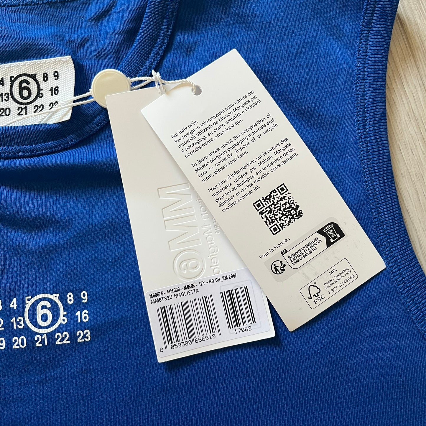 Close-up of a blue garment with a tag featuring a QR code and text on a white background.