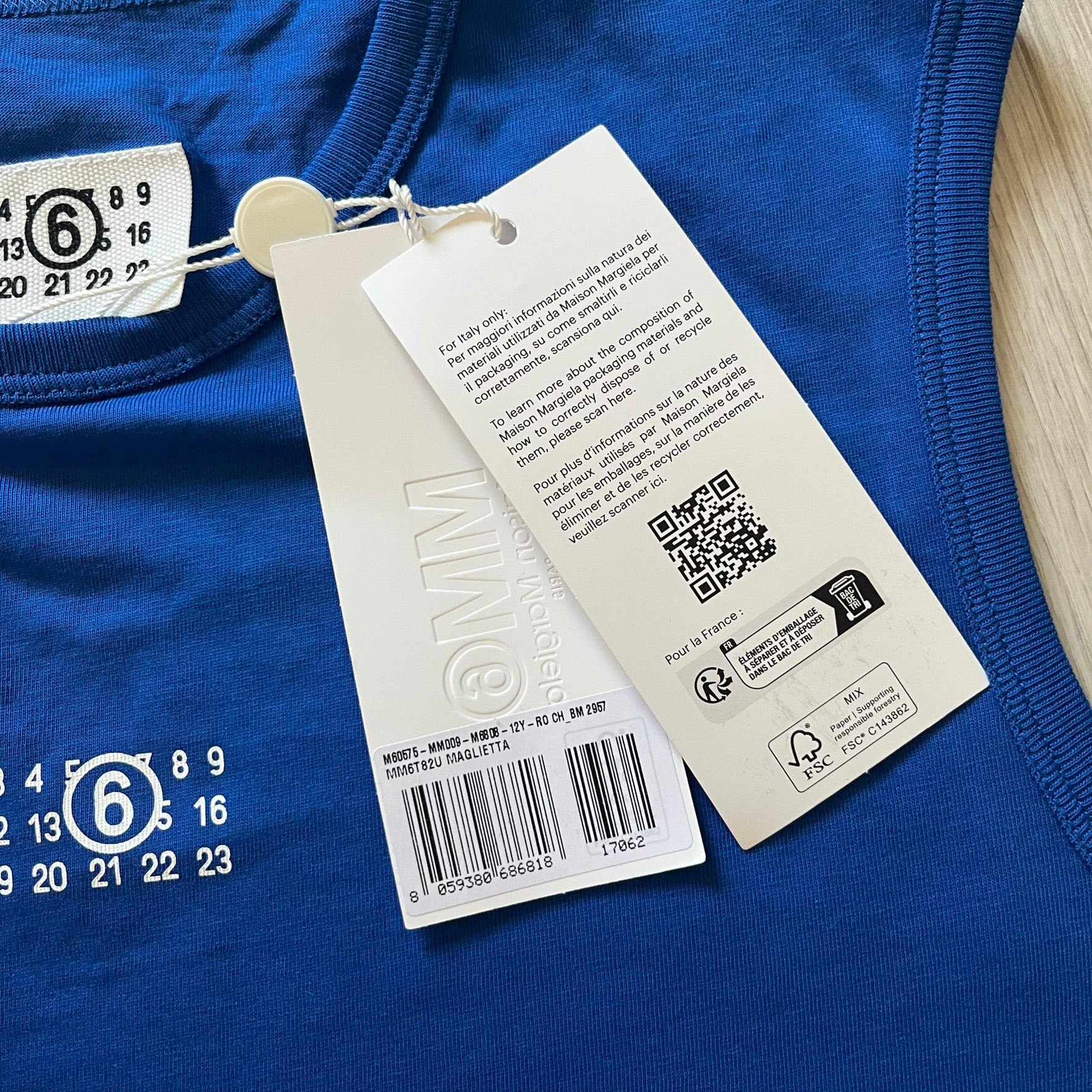 Close-up of a blue garment with a tag featuring a QR code and text on a white background.