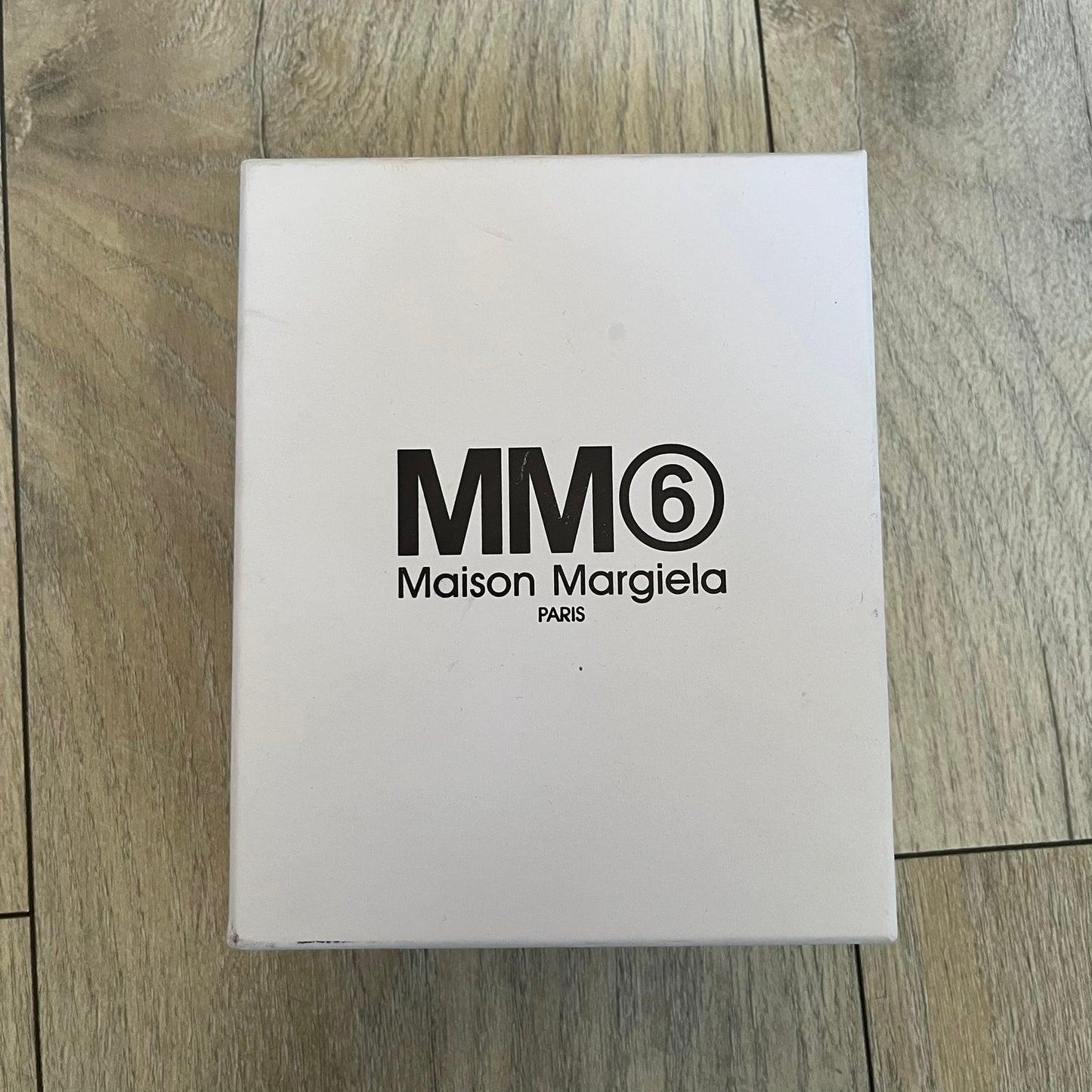 MM6 Maison Margiela White Side Cardholder is a white leather cardholder from MM6 Maison Margiela featuring a horizontal layout with a top zip compartment for coins. The side includes four card slots, while the front displays a mirrored Maison Margiela 6 logo. The item comes with original box and tags.