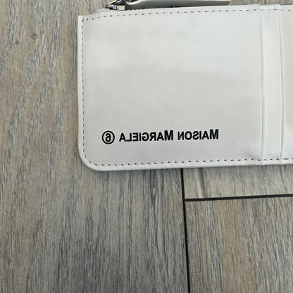 MM6 Maison Margiela White Side Cardholder is a white leather cardholder from MM6 Maison Margiela featuring a horizontal layout with a top zip compartment for coins. The side includes four card slots, while the front displays a mirrored Maison Margiela 6 logo. The item comes with original box and tags.