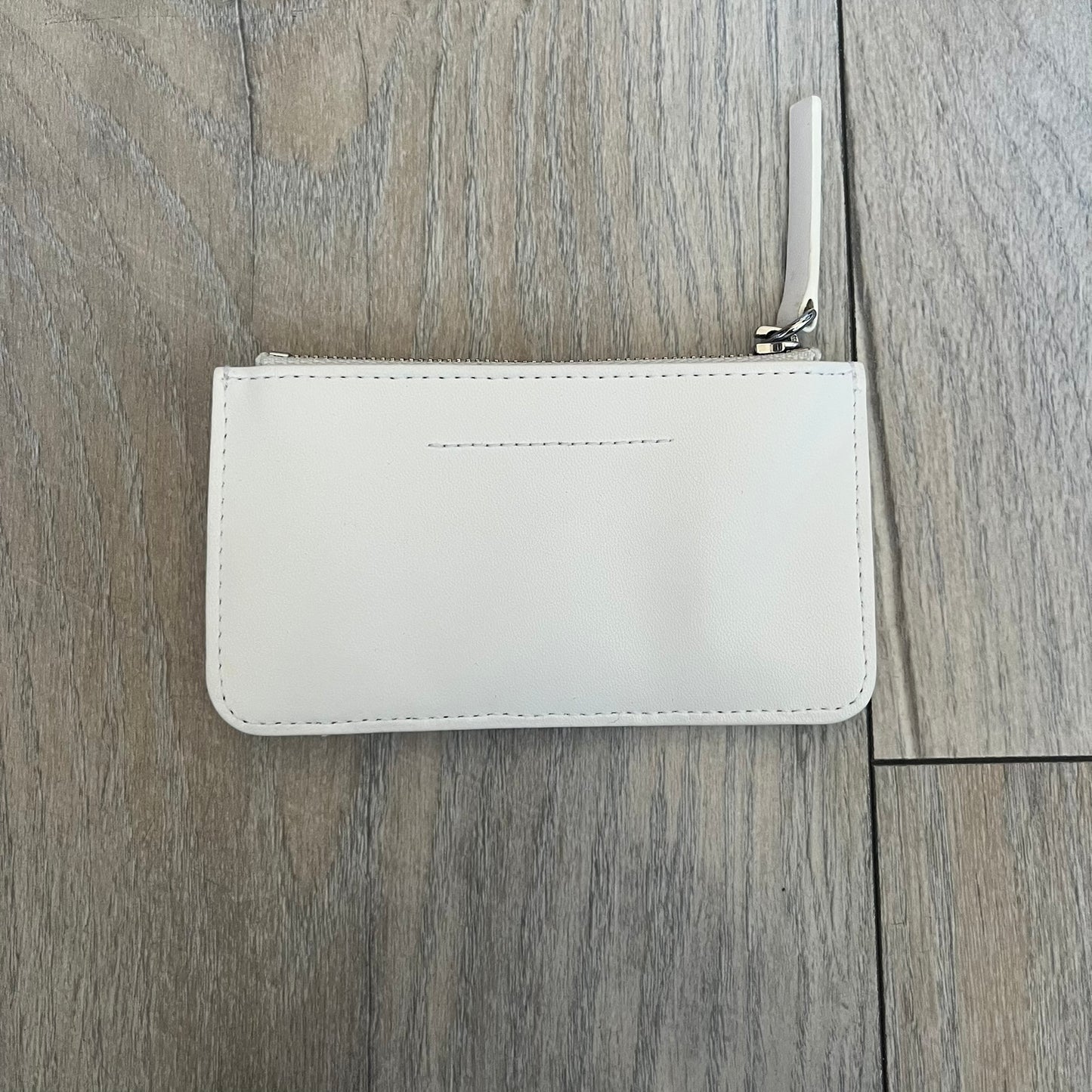MM6 Maison Margiela White Side Cardholder is a white leather cardholder from MM6 Maison Margiela featuring a horizontal layout with a top zip compartment for coins. The side includes four card slots, while the front displays a mirrored Maison Margiela 6 logo. The item comes with original box and tags.