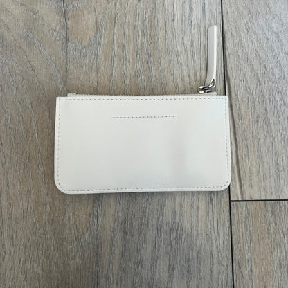 MM6 Maison Margiela White Side Cardholder is a white leather cardholder from MM6 Maison Margiela featuring a horizontal layout with a top zip compartment for coins. The side includes four card slots, while the front displays a mirrored Maison Margiela 6 logo. The item comes with original box and tags.