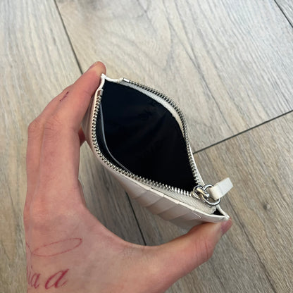 MM6 Maison Margiela White Side Cardholder is a white leather cardholder from MM6 Maison Margiela featuring a horizontal layout with a top zip compartment for coins. The side includes four card slots, while the front displays a mirrored Maison Margiela 6 logo. The item comes with original box and tags.